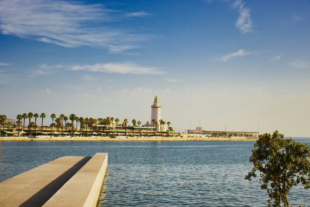 Vue panoramique d'une ville côtière avec un phare et des palmiers.